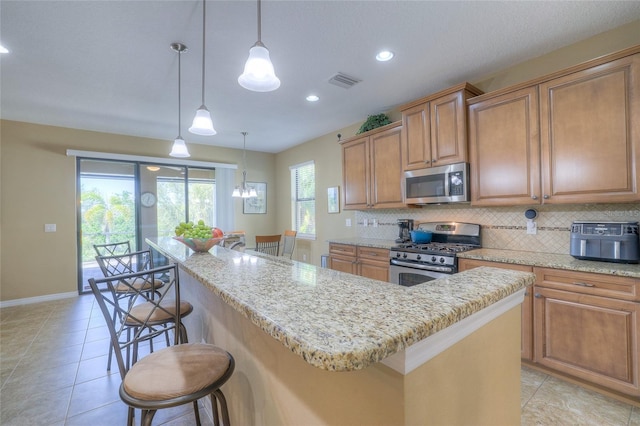 kitchen featuring a kitchen bar, visible vents, backsplash, a kitchen island, and stainless steel appliances