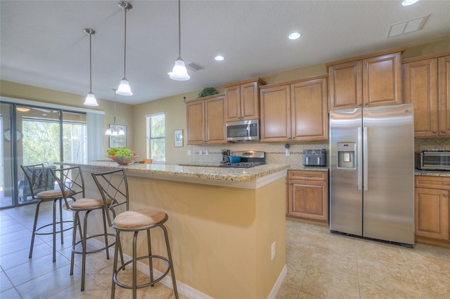 kitchen with tasteful backsplash, brown cabinetry, visible vents, and stainless steel appliances