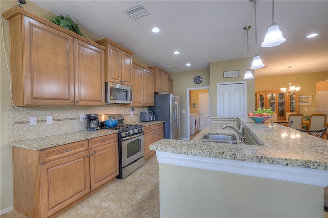 kitchen with visible vents, a sink, washing machine and dryer, stainless steel appliances, and decorative backsplash