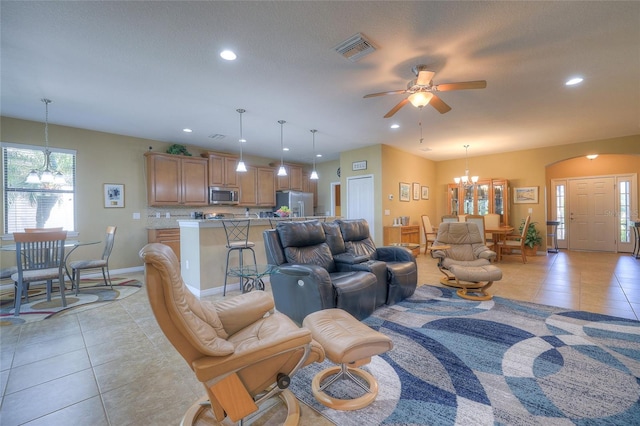 living area featuring recessed lighting, light tile patterned floors, ceiling fan with notable chandelier, and visible vents