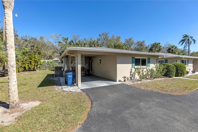 view of front of house with stucco siding, a carport, a front yard, and aphalt driveway