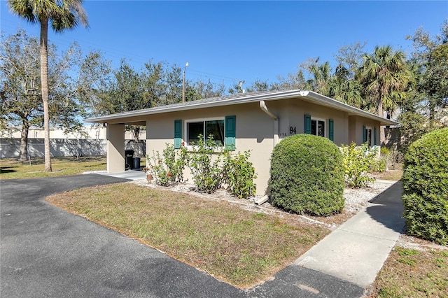 single story home featuring stucco siding, a front lawn, and fence