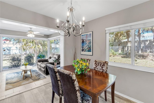 dining space featuring light wood-style floors, ceiling fan with notable chandelier, and baseboards