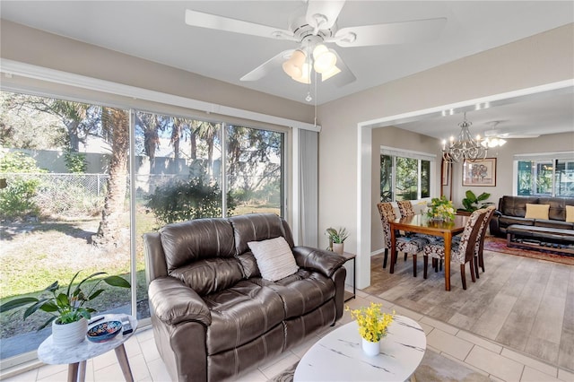 living area with a wealth of natural light, light tile patterned floors, and ceiling fan with notable chandelier