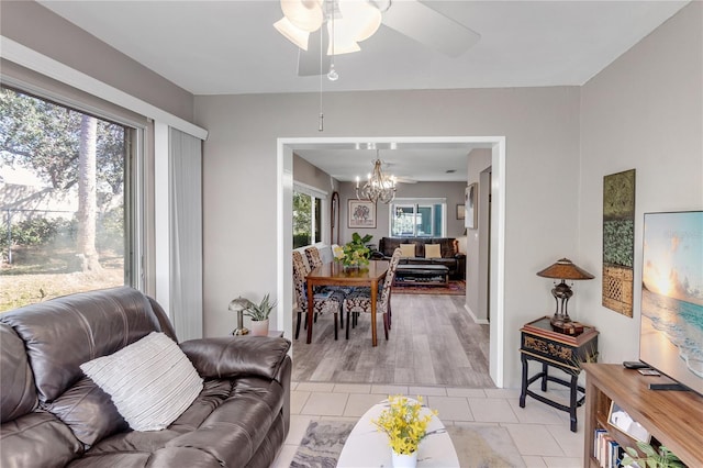 living area with light tile patterned floors and ceiling fan with notable chandelier