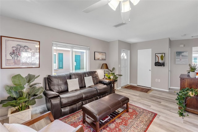 living room featuring light wood-type flooring, baseboards, and a ceiling fan