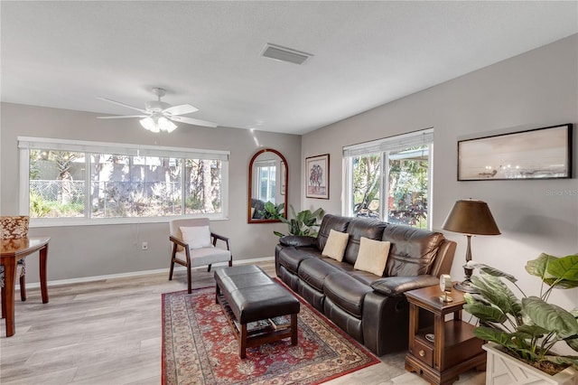 living area with visible vents, baseboards, light wood-style floors, and ceiling fan