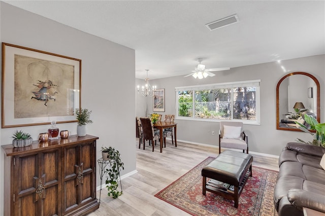 living room with visible vents, ceiling fan with notable chandelier, light wood-type flooring, and baseboards