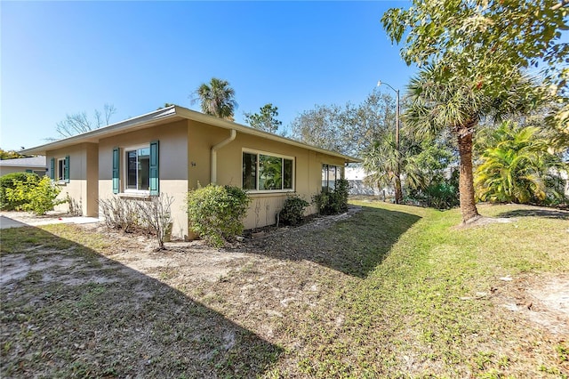 view of side of home with a yard and stucco siding