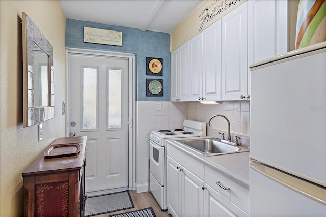 kitchen featuring white cabinetry, white appliances, light countertops, and a sink