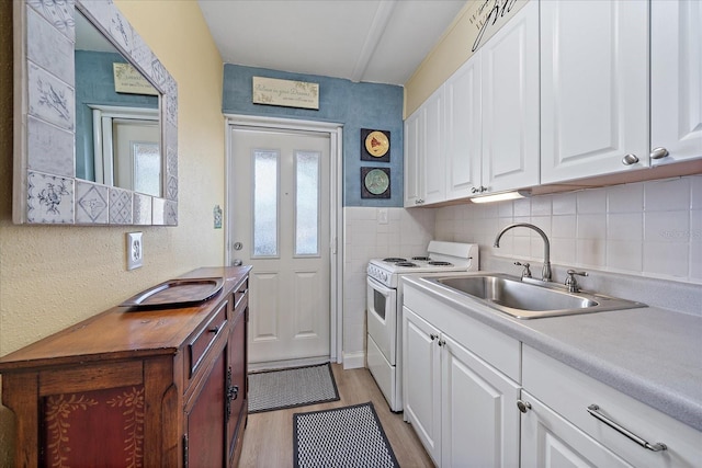 kitchen with a sink, light countertops, white cabinetry, light wood-type flooring, and white range with electric stovetop