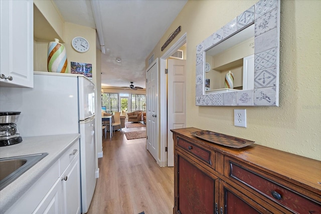 kitchen featuring a sink, white cabinetry, butcher block counters, light wood finished floors, and ceiling fan