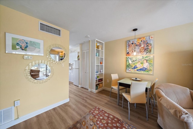 dining area featuring visible vents, baseboards, and wood finished floors