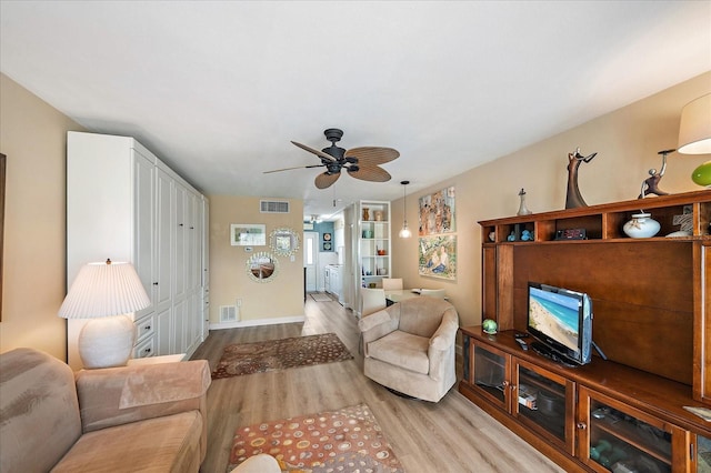 living area with a ceiling fan, visible vents, and light wood finished floors