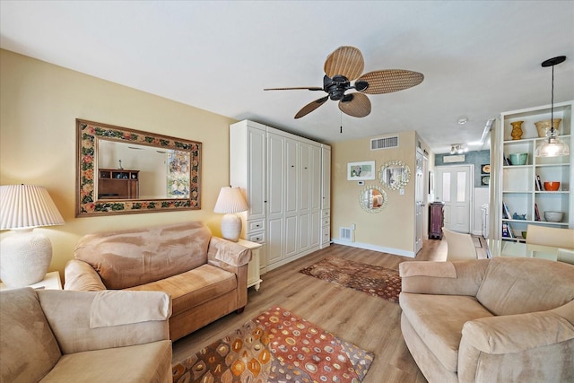 living area with visible vents, baseboards, light wood-type flooring, and ceiling fan