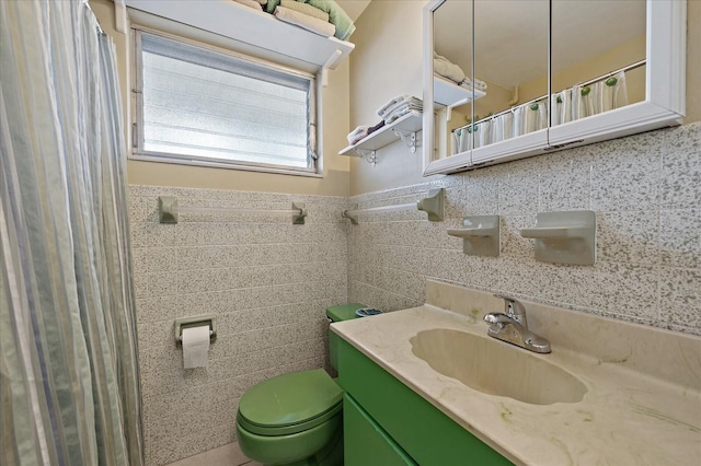 bathroom featuring vanity, tile walls, toilet, and a wainscoted wall