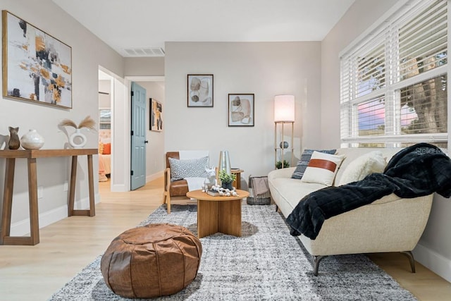 living room with visible vents, baseboards, and light wood-style floors