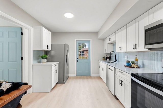 kitchen with light countertops, light wood finished floors, appliances with stainless steel finishes, and a sink