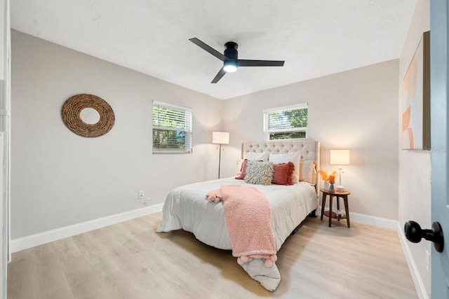 bedroom featuring multiple windows, light wood-style floors, and baseboards