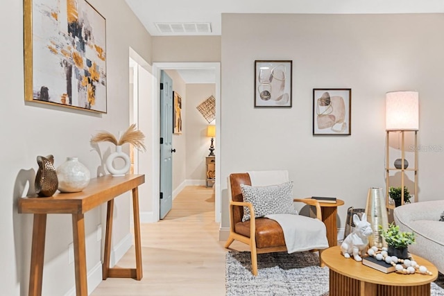 living area featuring visible vents, light wood-style flooring, and baseboards