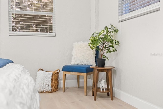 sitting room featuring baseboards, a healthy amount of sunlight, and wood finished floors