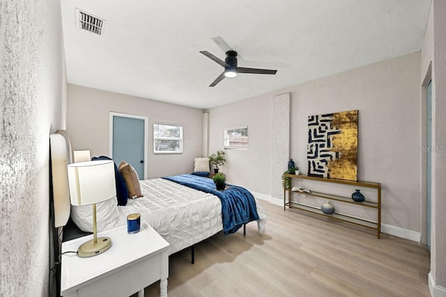 bedroom featuring ceiling fan, visible vents, baseboards, and wood finished floors