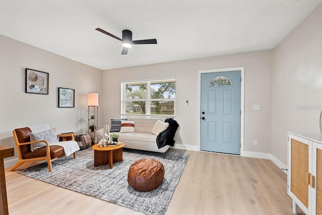 living area with baseboards, light wood-style floors, and a ceiling fan