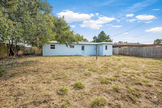 back of property featuring stucco siding, a lawn, and a fenced backyard