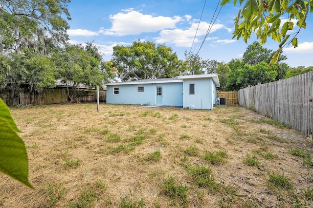 back of property featuring stucco siding, cooling unit, a lawn, and a fenced backyard