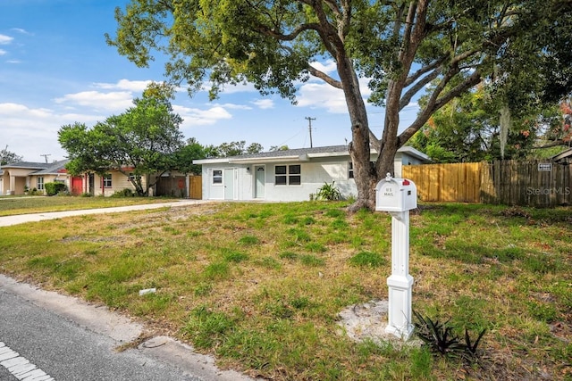 ranch-style home with a front lawn and fence