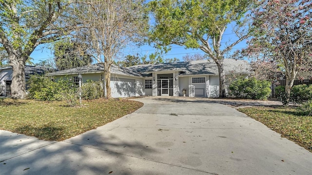 ranch-style home with stucco siding, a garage, concrete driveway, and a front lawn