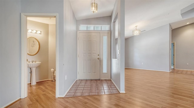 entrance foyer featuring an inviting chandelier, wood finished floors, baseboards, and vaulted ceiling