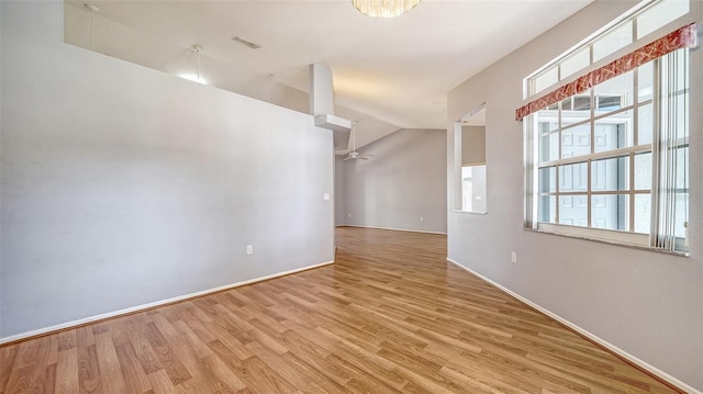 spare room featuring a ceiling fan, wood finished floors, visible vents, baseboards, and vaulted ceiling