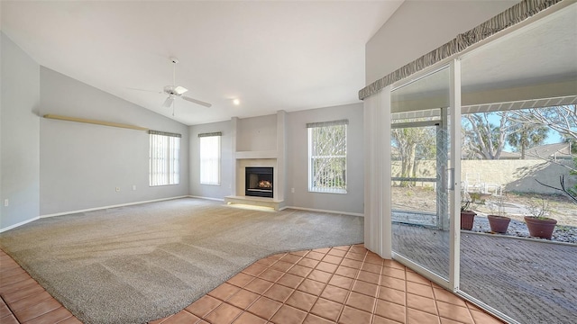 living area featuring a fireplace with raised hearth, light colored carpet, lofted ceiling, light tile patterned flooring, and a ceiling fan