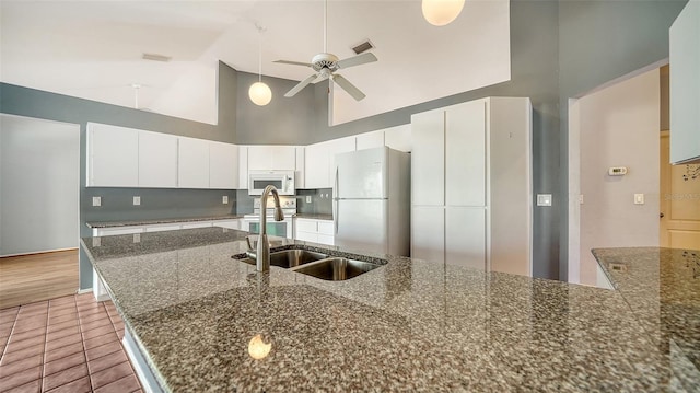 kitchen featuring white appliances, visible vents, ceiling fan, a sink, and white cabinets