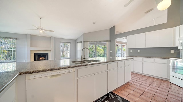 kitchen with white appliances, a ceiling fan, plenty of natural light, a lit fireplace, and a sink