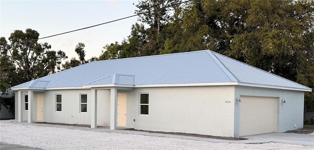 view of front of house with stucco siding, metal roof, and a garage