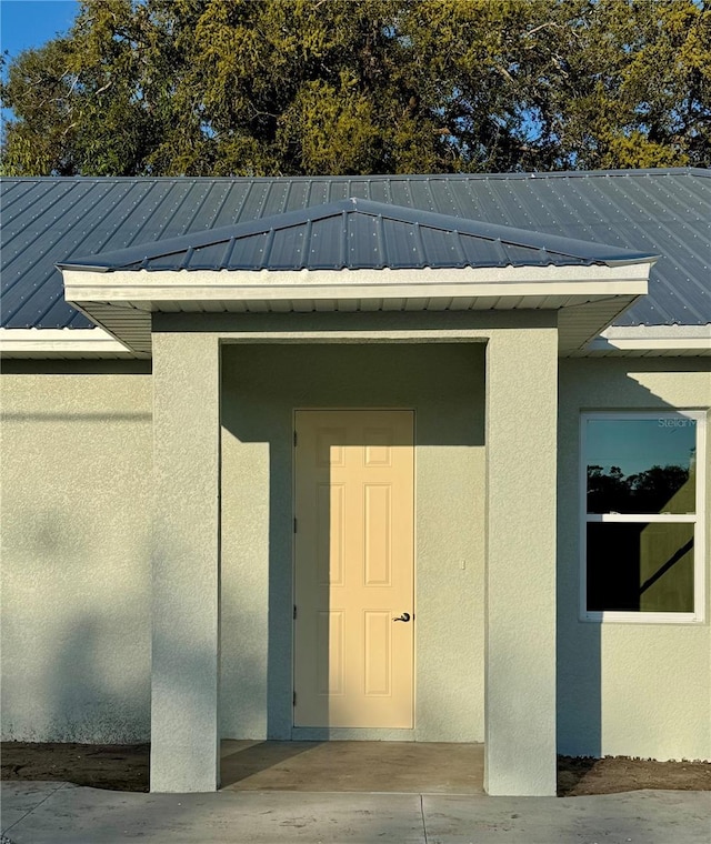 property entrance featuring stucco siding and metal roof