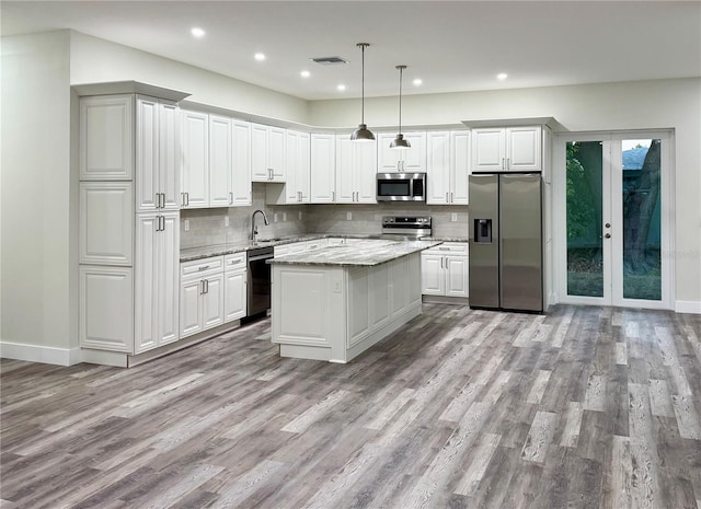 kitchen featuring visible vents, decorative backsplash, light wood-style floors, stainless steel appliances, and a sink