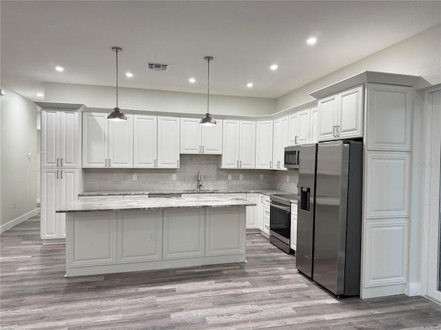 kitchen with visible vents, a center island, decorative backsplash, appliances with stainless steel finishes, and a sink