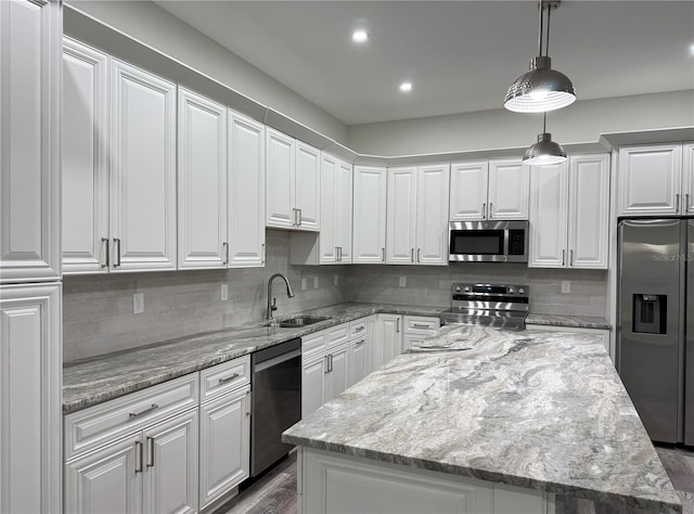 kitchen featuring a sink, decorative backsplash, stainless steel appliances, white cabinets, and a center island