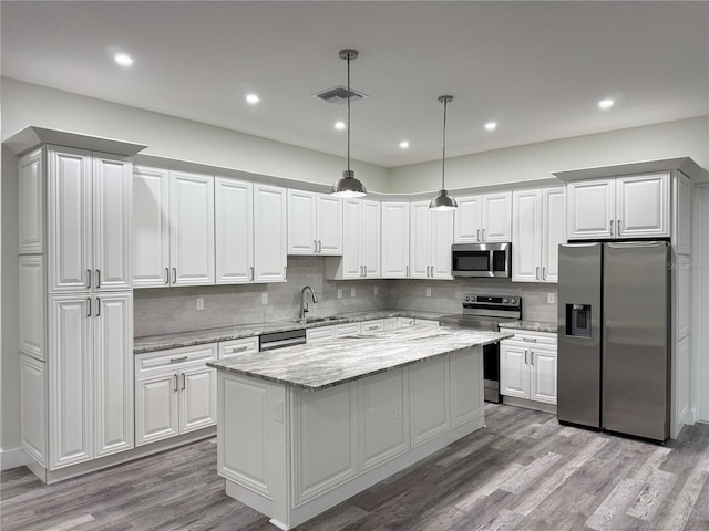 kitchen featuring visible vents, a center island, decorative backsplash, appliances with stainless steel finishes, and light wood-style floors