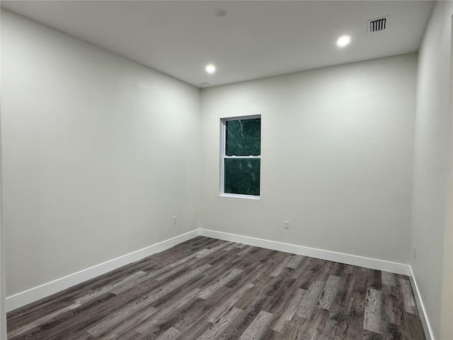 empty room featuring dark wood finished floors, recessed lighting, baseboards, and visible vents