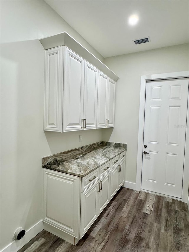 clothes washing area featuring visible vents, dark wood-type flooring, and baseboards