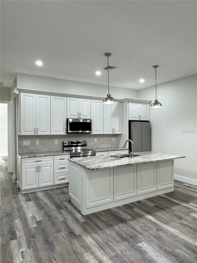 kitchen featuring a sink, backsplash, a center island with sink, stainless steel appliances, and dark wood-style flooring