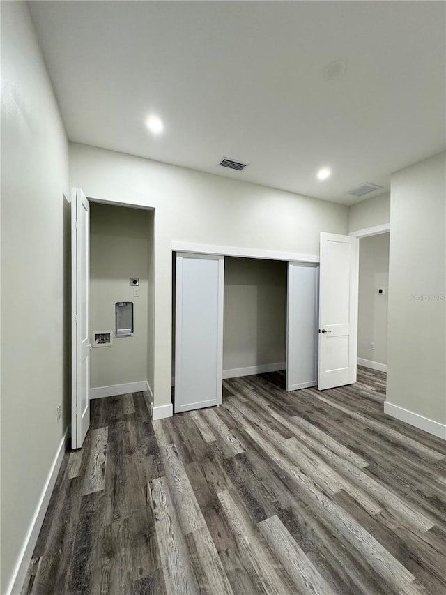 unfurnished bedroom with a closet, baseboards, visible vents, and dark wood-style flooring