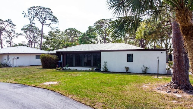411 S Oxford Dr Unit 411, Nokomis, FL 34275 - rear view of house with a tile roof, a yard, a sunroom, and stucco siding