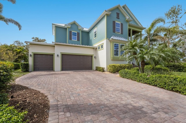 view of front of house with decorative driveway, a garage, and stucco siding