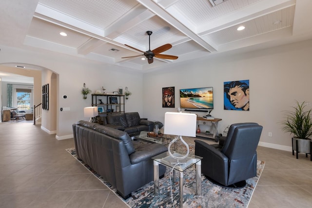 living area with light tile patterned floors, baseboards, arched walkways, and a ceiling fan