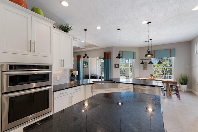 kitchen featuring a sink, stainless steel appliances, backsplash, and white cabinets